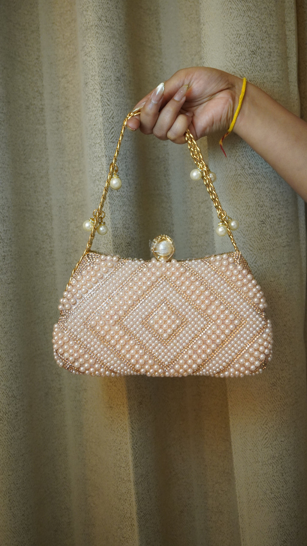 Pink pearl beaded clutch angled view with golden-toned chain handle