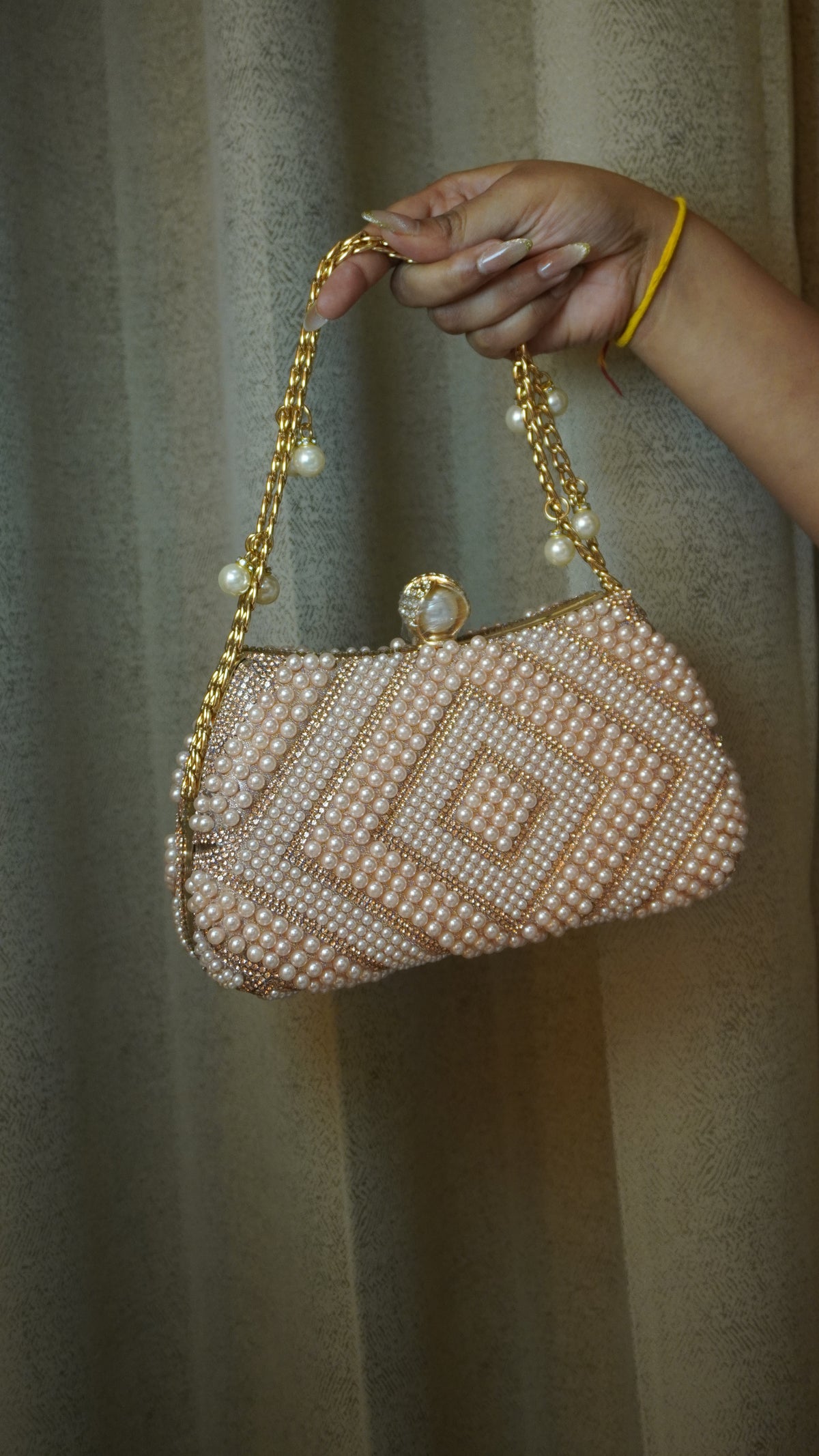 Pink pearl beaded clutch with pearl-style clasp and dangling chain charms