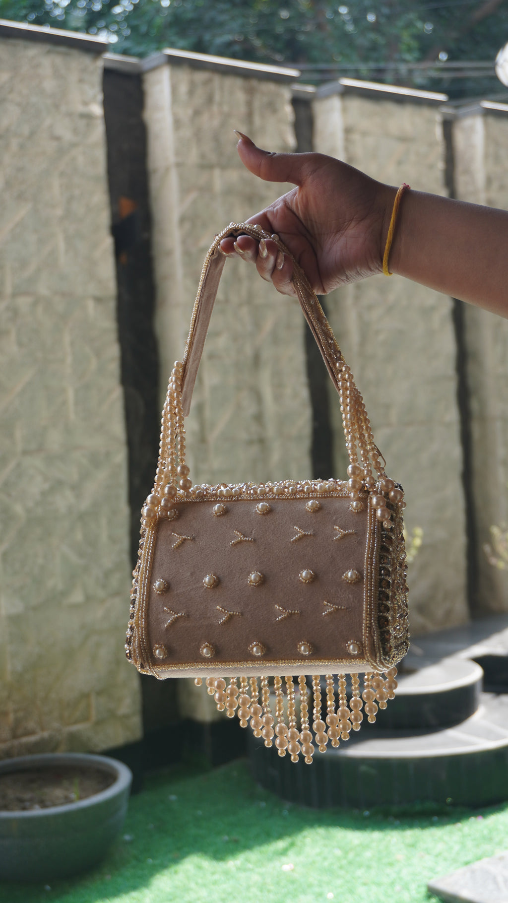 Rose-gold handworked beaded clutch with embroidered handle and cascading bead fringe, front view