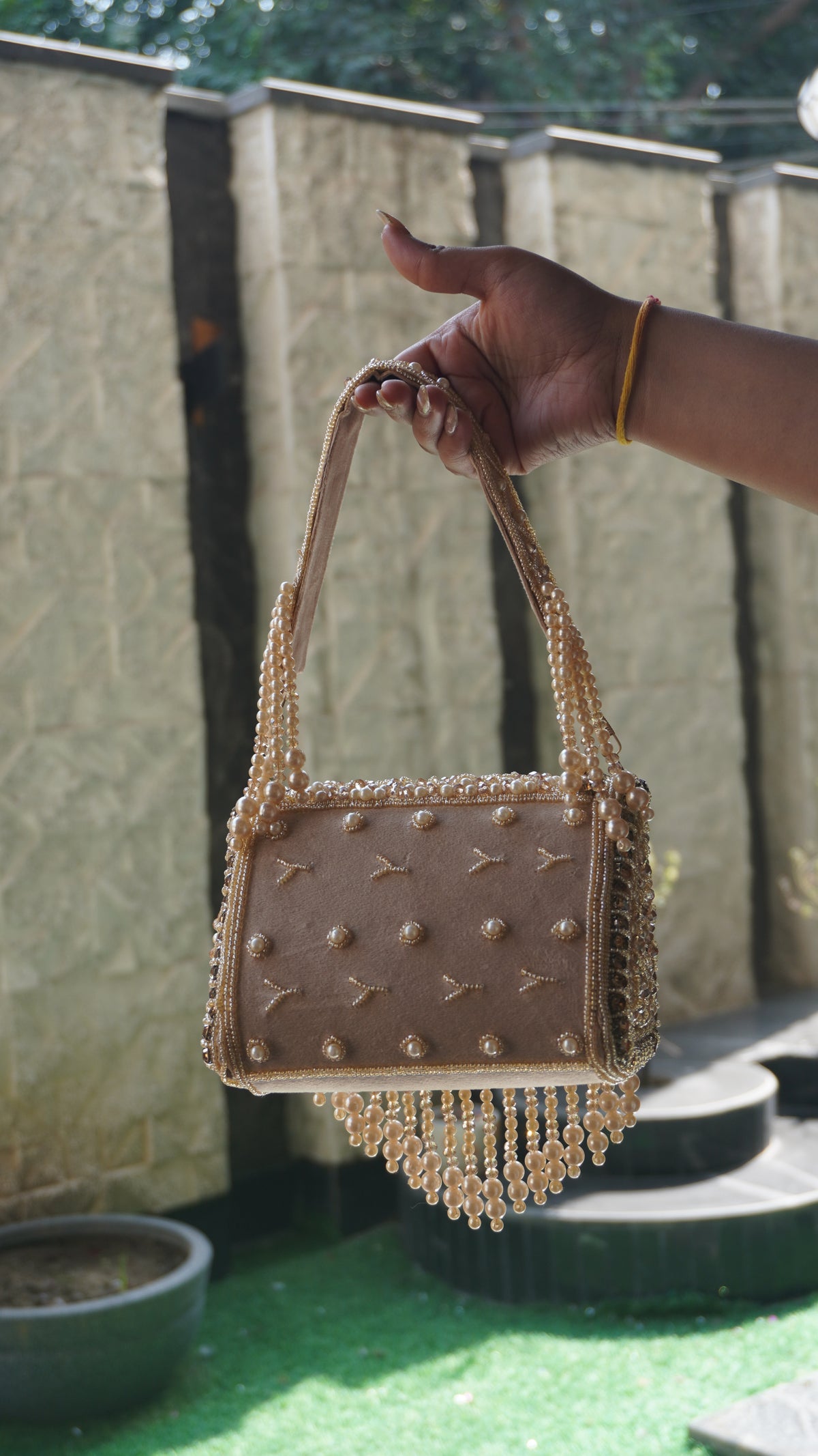 Rose-gold handworked beaded clutch with embroidered handle and cascading bead fringe, front view