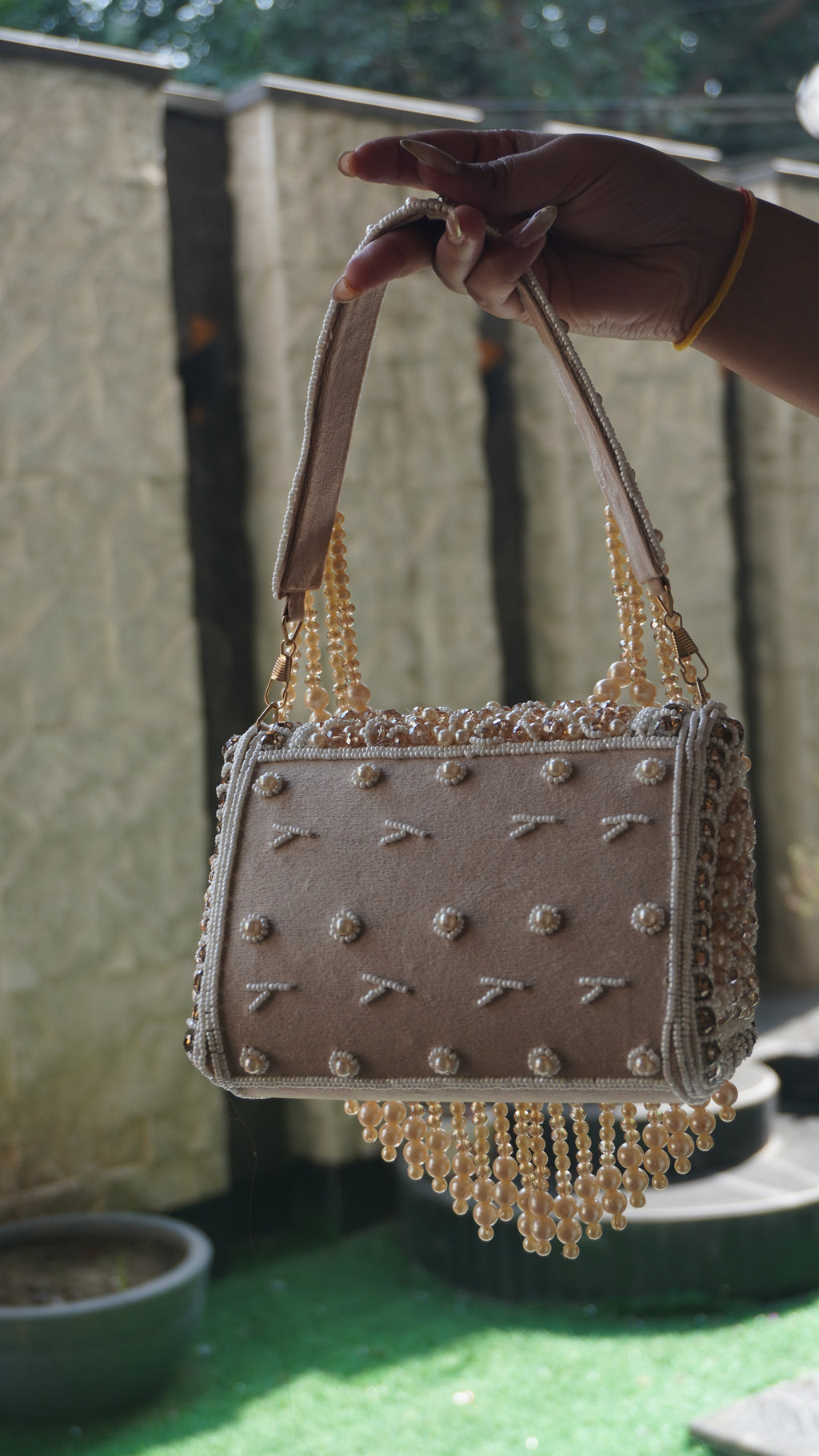 White-gold coloured handworked beaded clutch with embroidered handle and hanging bead fringe, front view