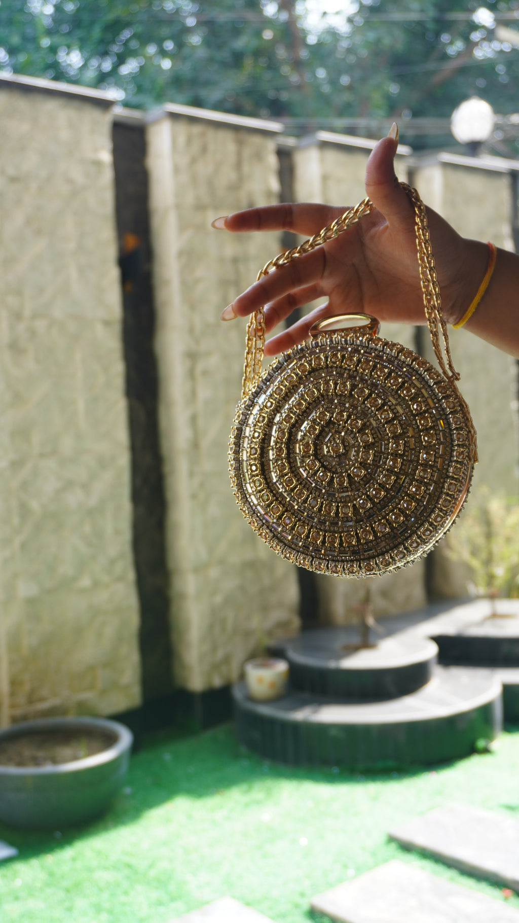 Golden circular crystal bridal clutch showing decorative top clasp and chain carry handle