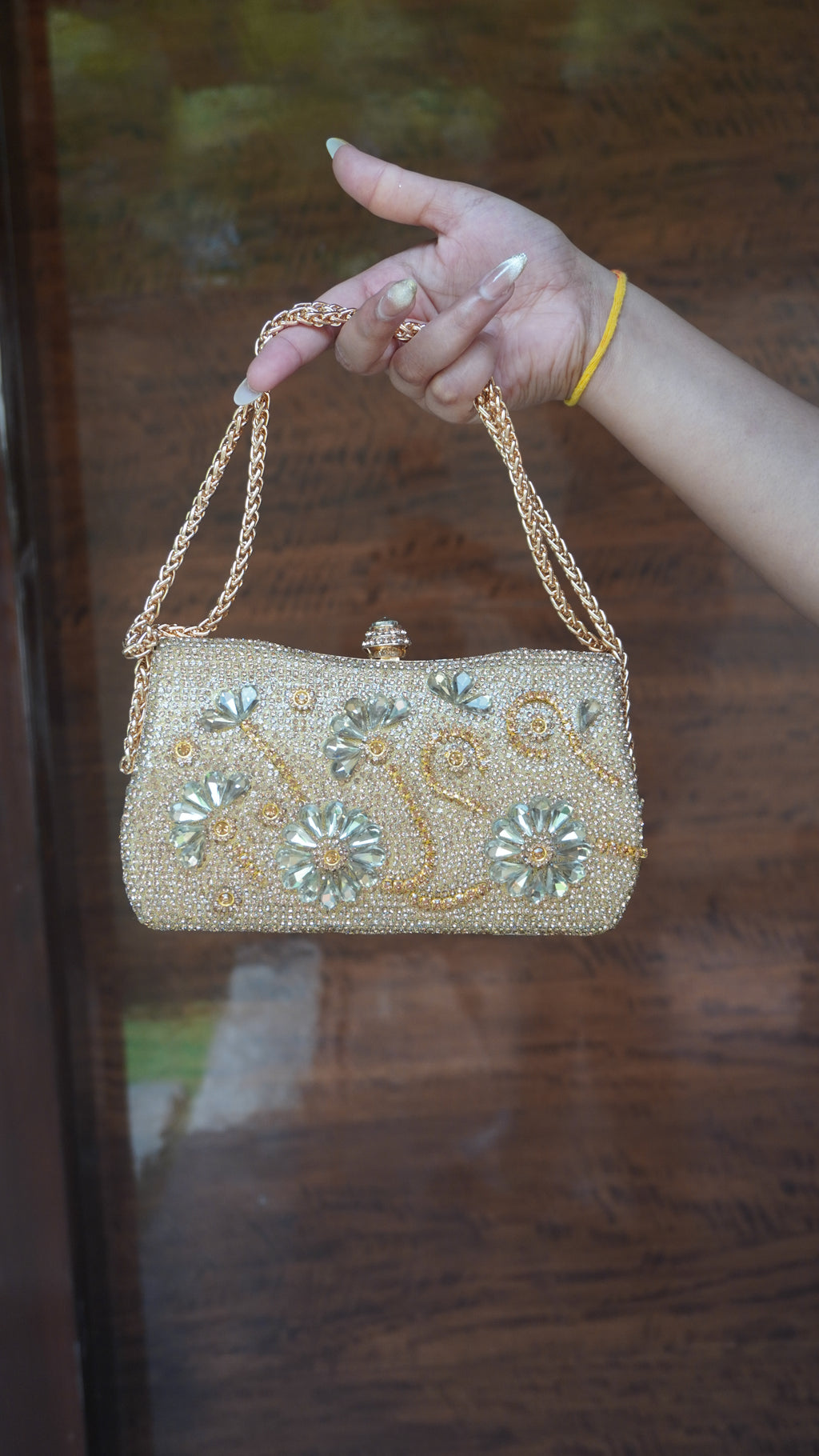 Golden flower-embroidered clutch with floral embellishments and chain carry handle