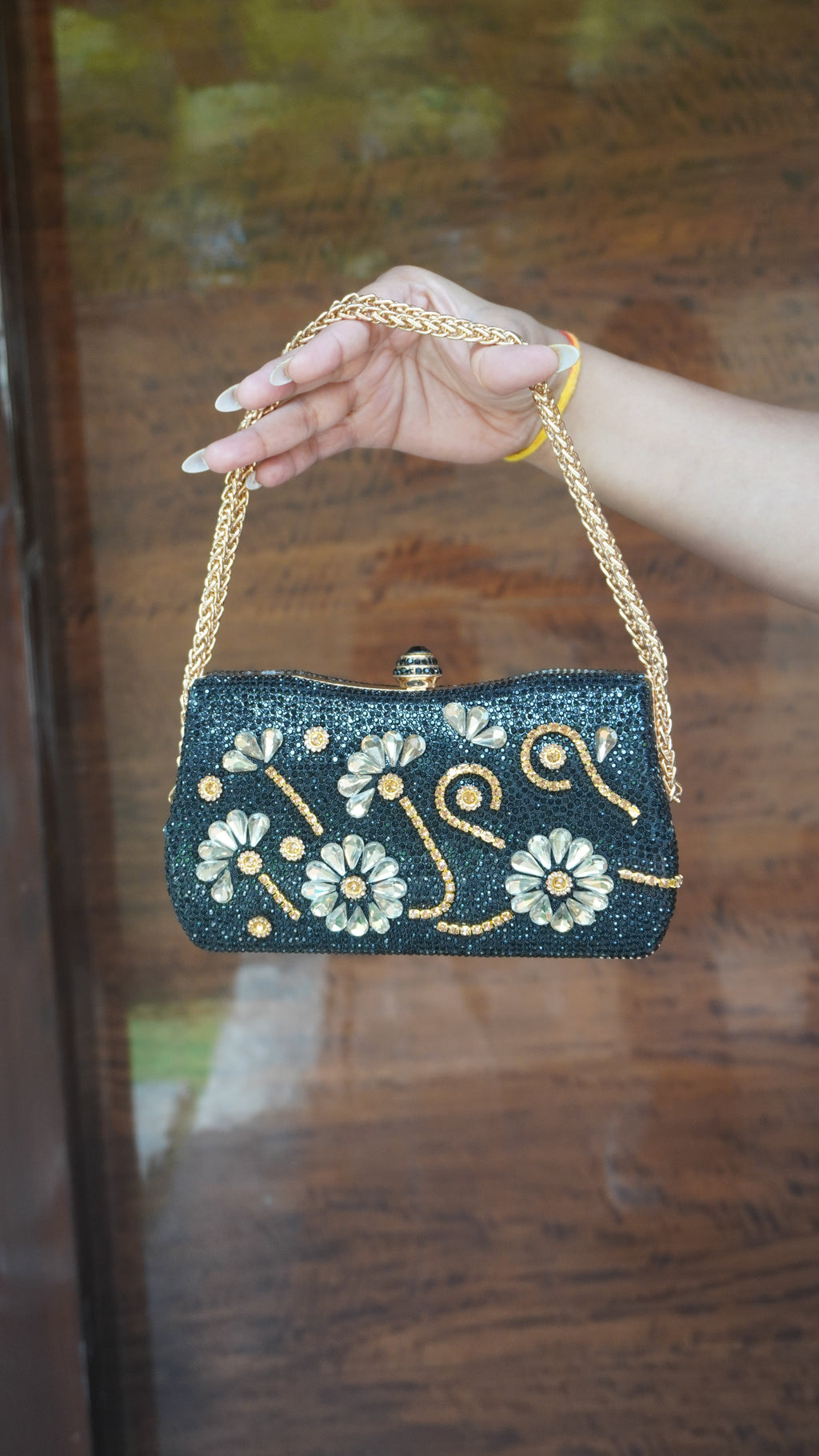Black flower-embroidered clutch with golden detailing and golden chain carry handle