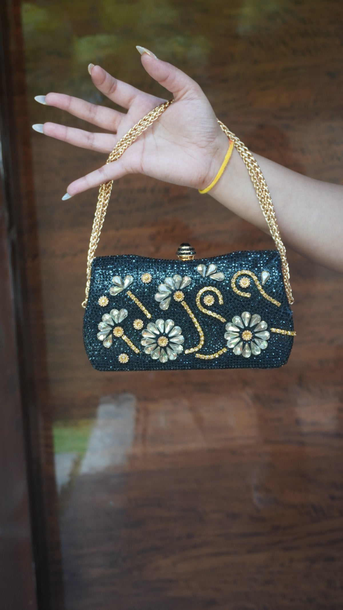 Black floral embroidered clutch showing petal-shaped embellishments and decorative top clasp