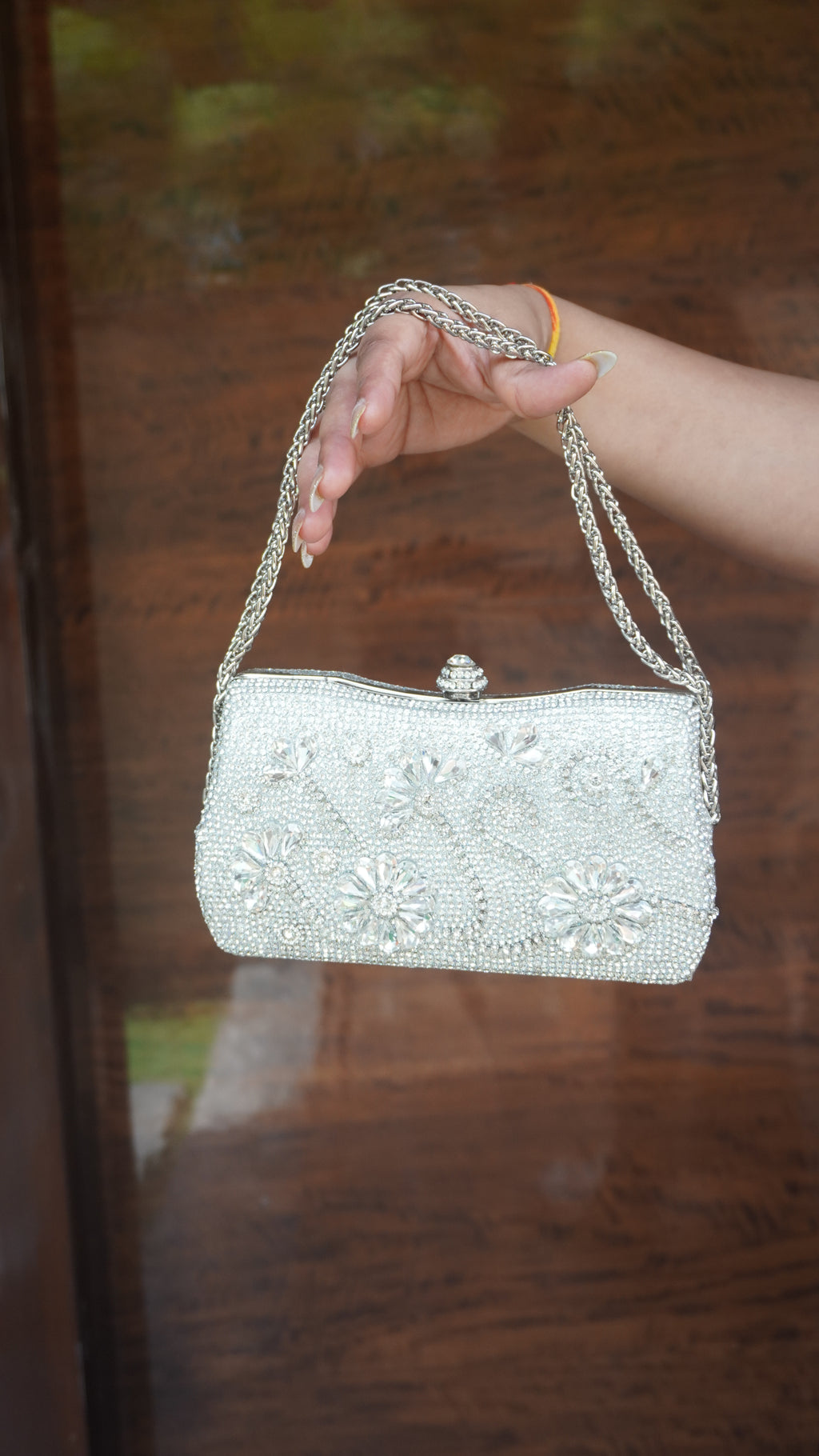 Silver flower-embroidered clutch with floral embellishments and chain carry handle