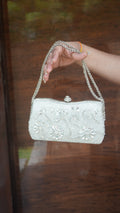 Silver flower-embroidered clutch with floral embellishments and chain carry handle
