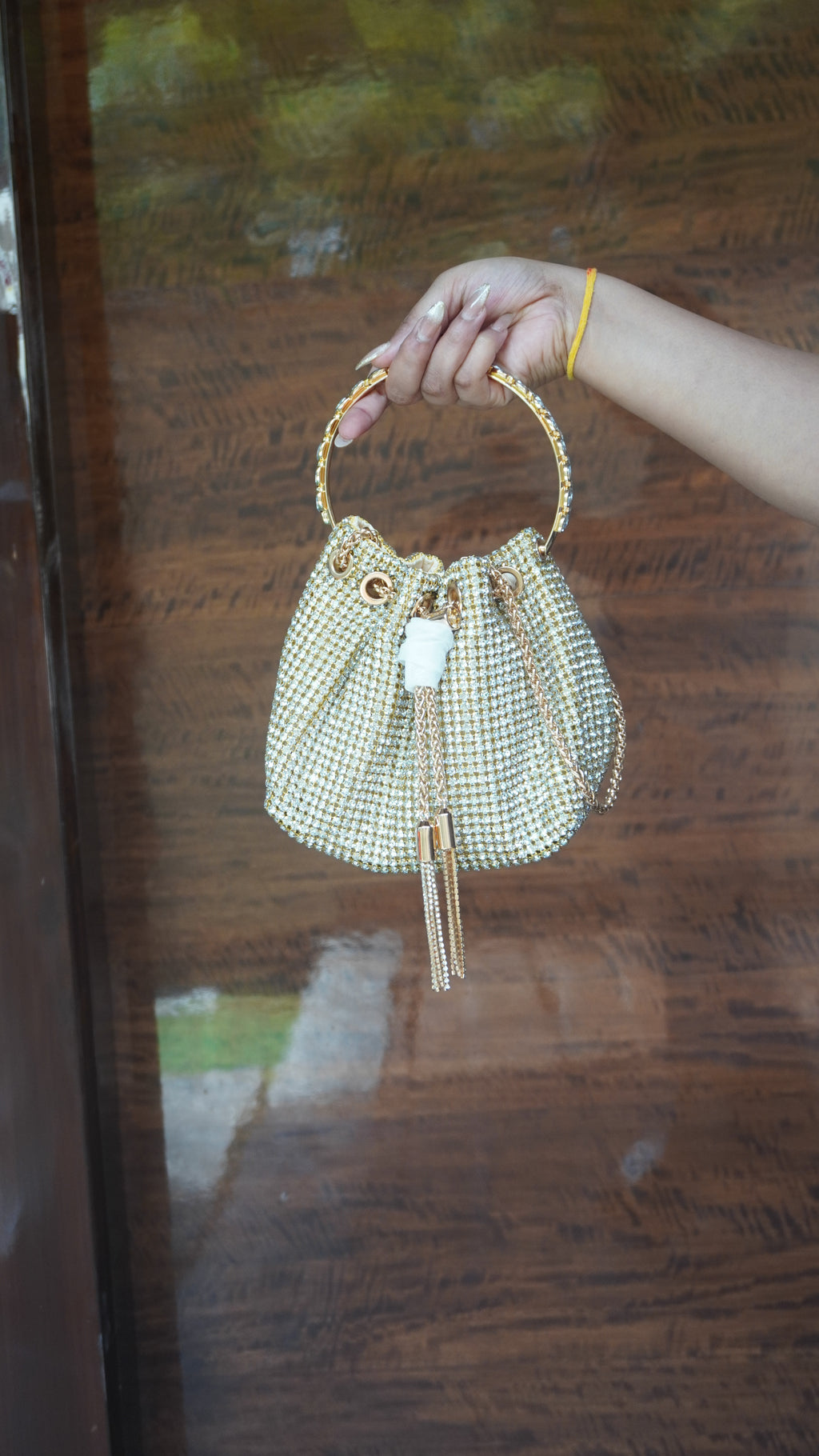Golden potli with all-over small beadwork, circular carry handle and hanging tassels