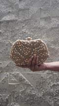 Golden party clutch with leaf-shaped sparkling accents and all-over decorative work