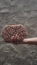 Pink party clutch with sparkling leaf-shaped accents and all-over decorative work
