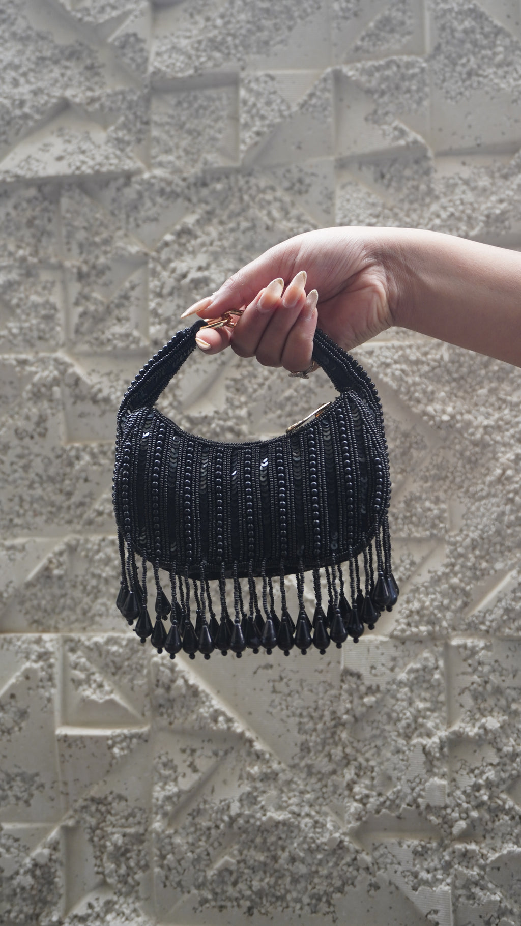 Black small bag showing bead and sequin detailing and hanging teardrop fringe