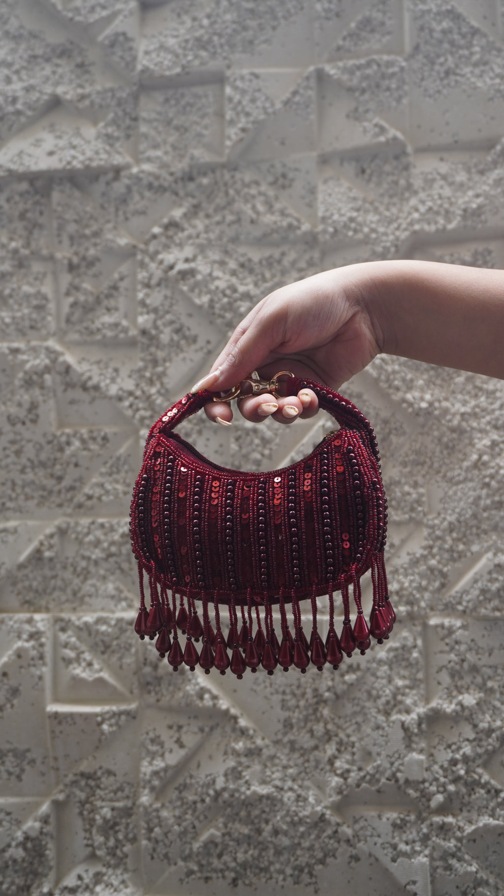 Red crescent-shaped small bag showing bead and sequin detailing and teardrop fringe