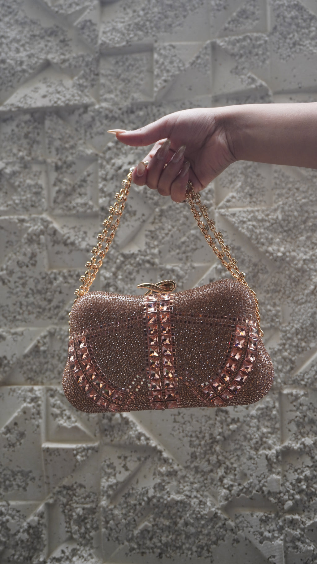 Rose pink embellished party clutch with gold-toned chain handle and bow-shaped clasp
