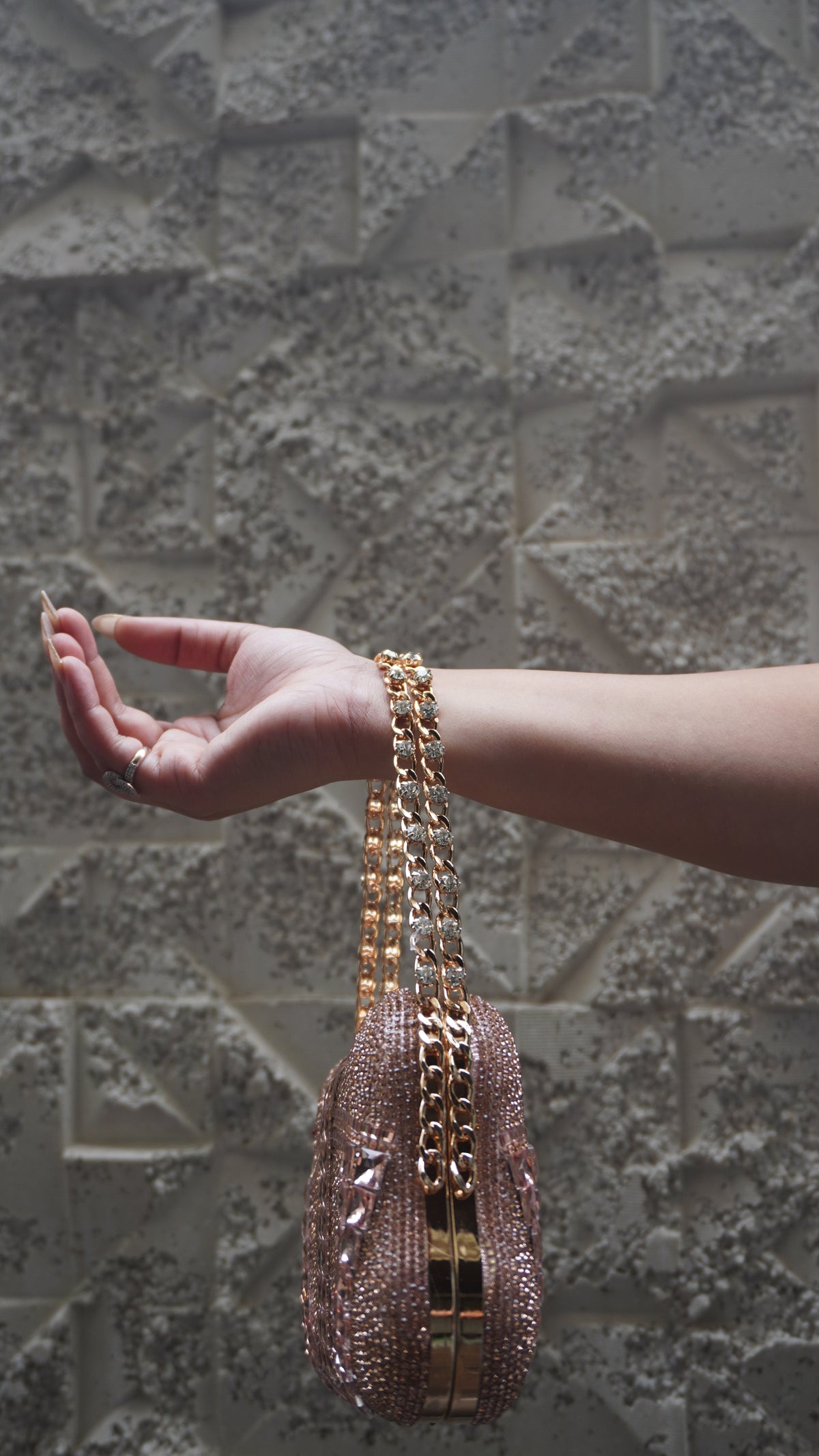 Side view of rose pink embellished clutch with gold-toned frame and chain handle