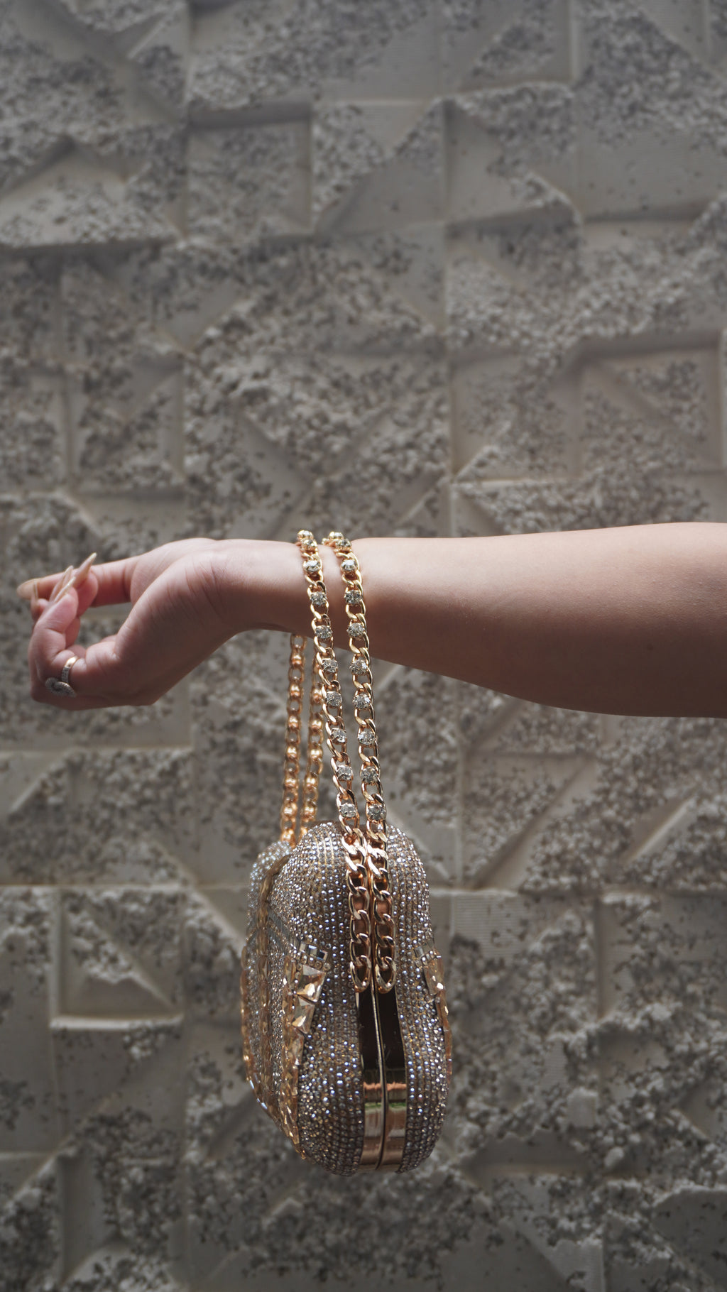 Side view of golden embellished clutch with gold-toned frame and chain handle