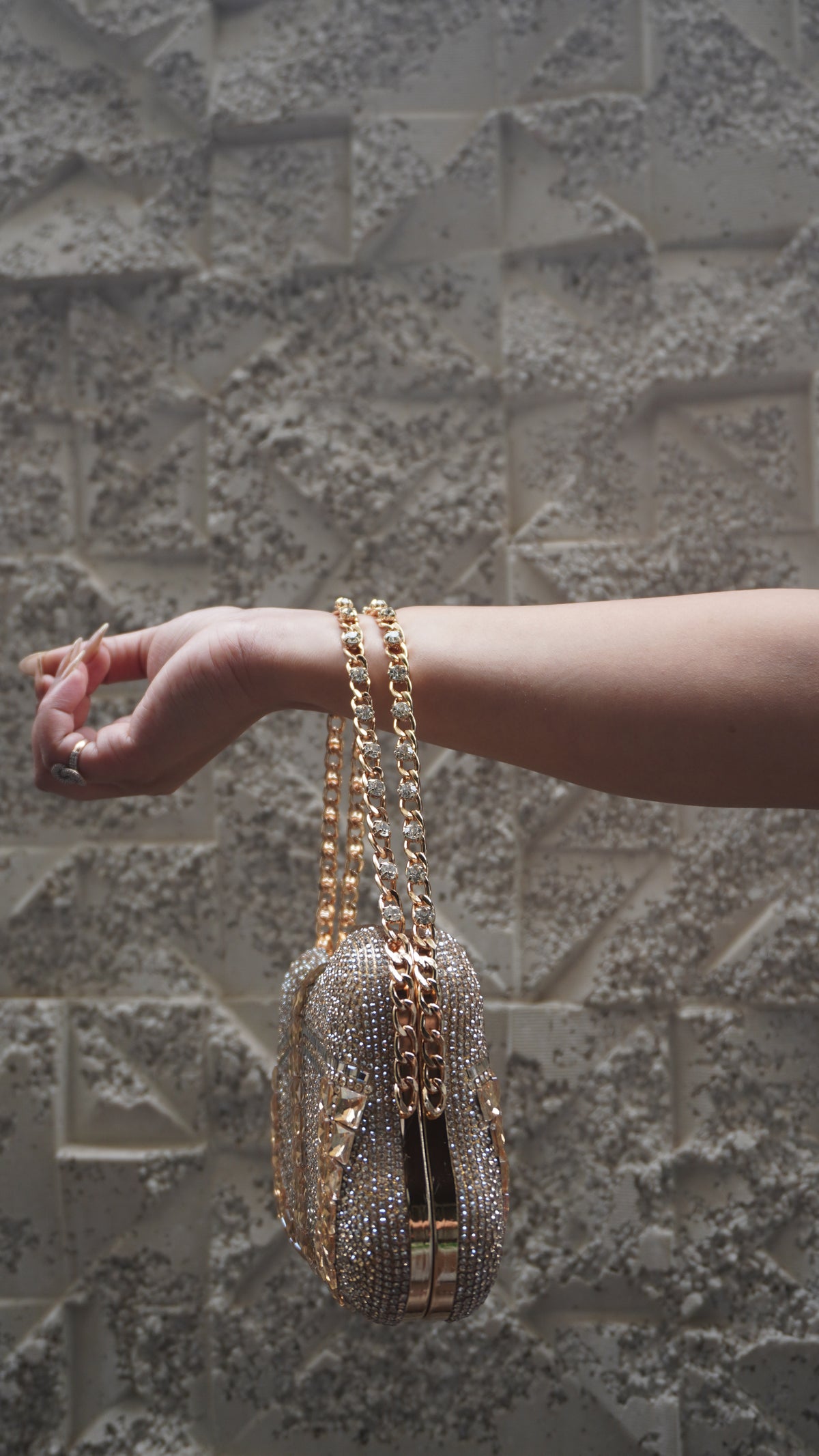 Side view of golden embellished clutch with gold-toned frame and chain handle