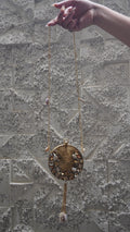 Golden brass round embellished sling bag with long chain strap and hanging tassel