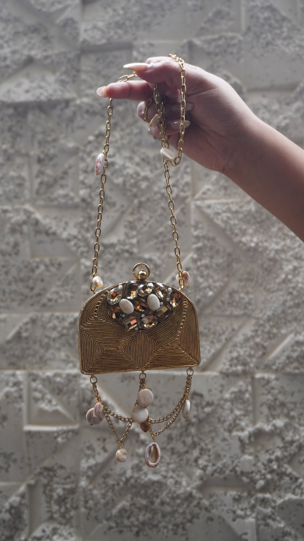 Close view of golden brass arched bag with geometric detailing and faceted embellishments