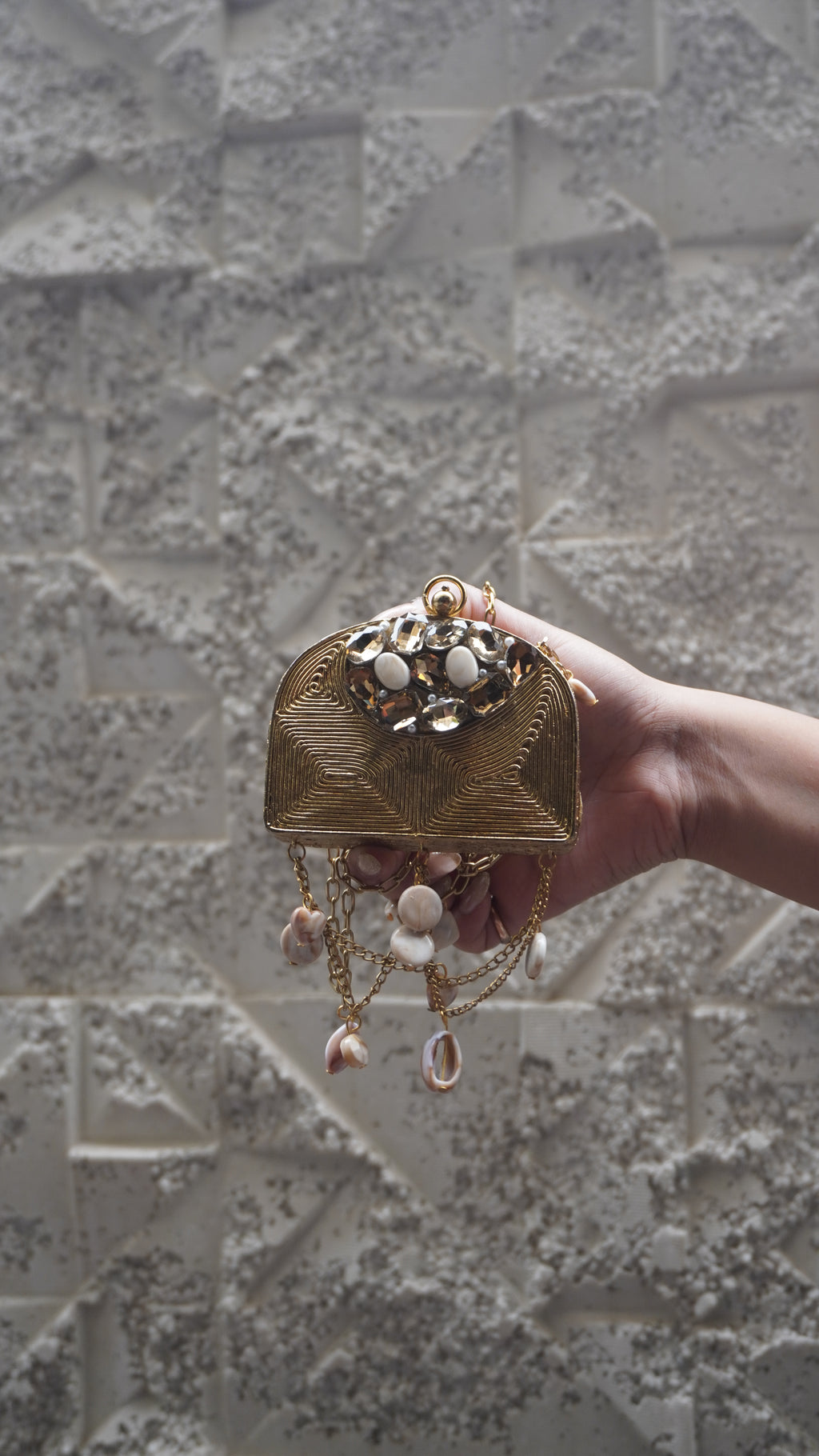 Golden arched embellished sling bag with draped chains and hanging charms