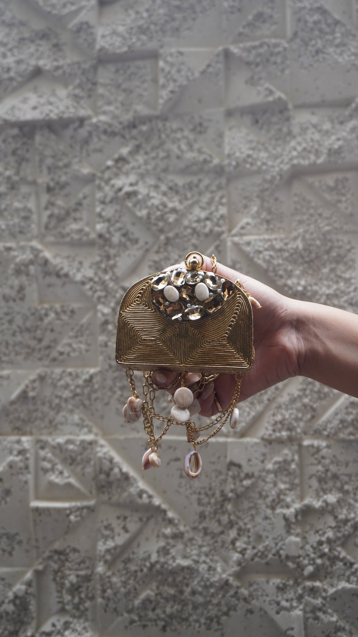 Golden arched embellished sling bag with draped chains and hanging charms