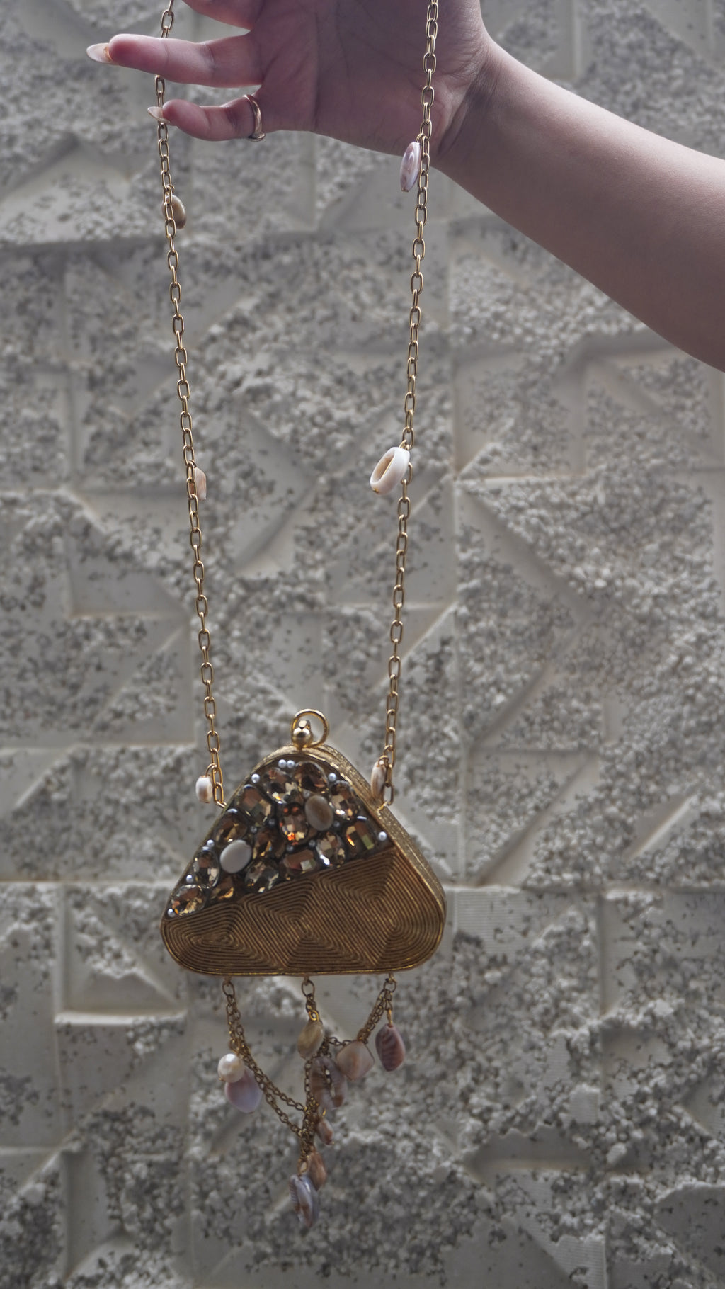 Golden triangular brass bag with long chain strap and draped charm chains